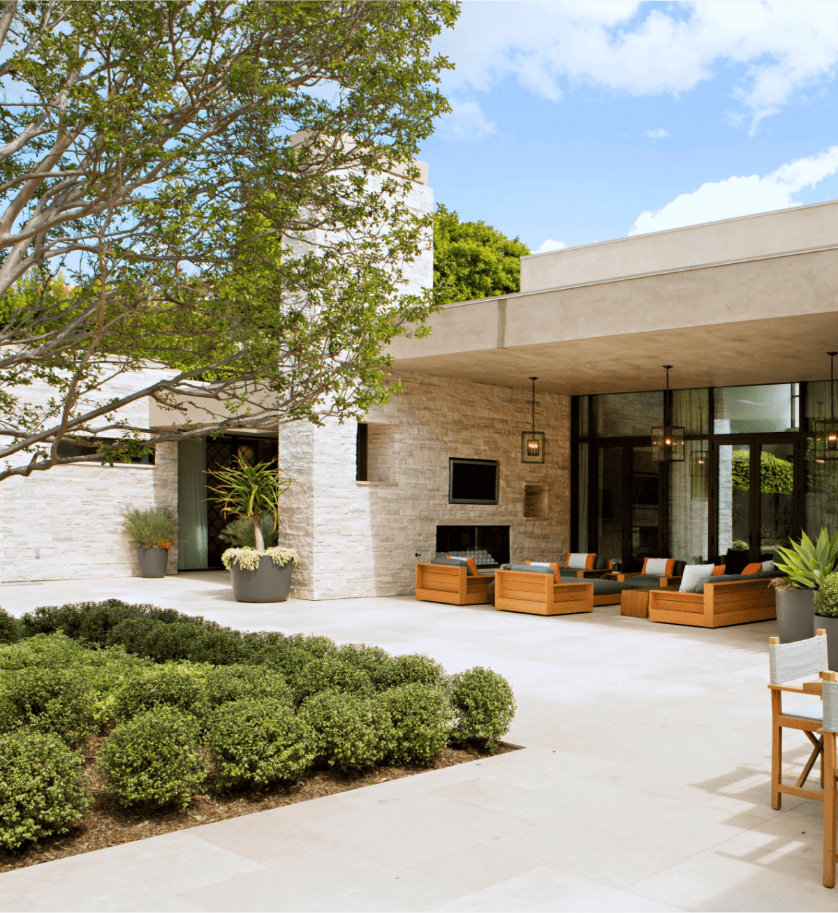 A contemporary house with a patio and a tree in the front yard.